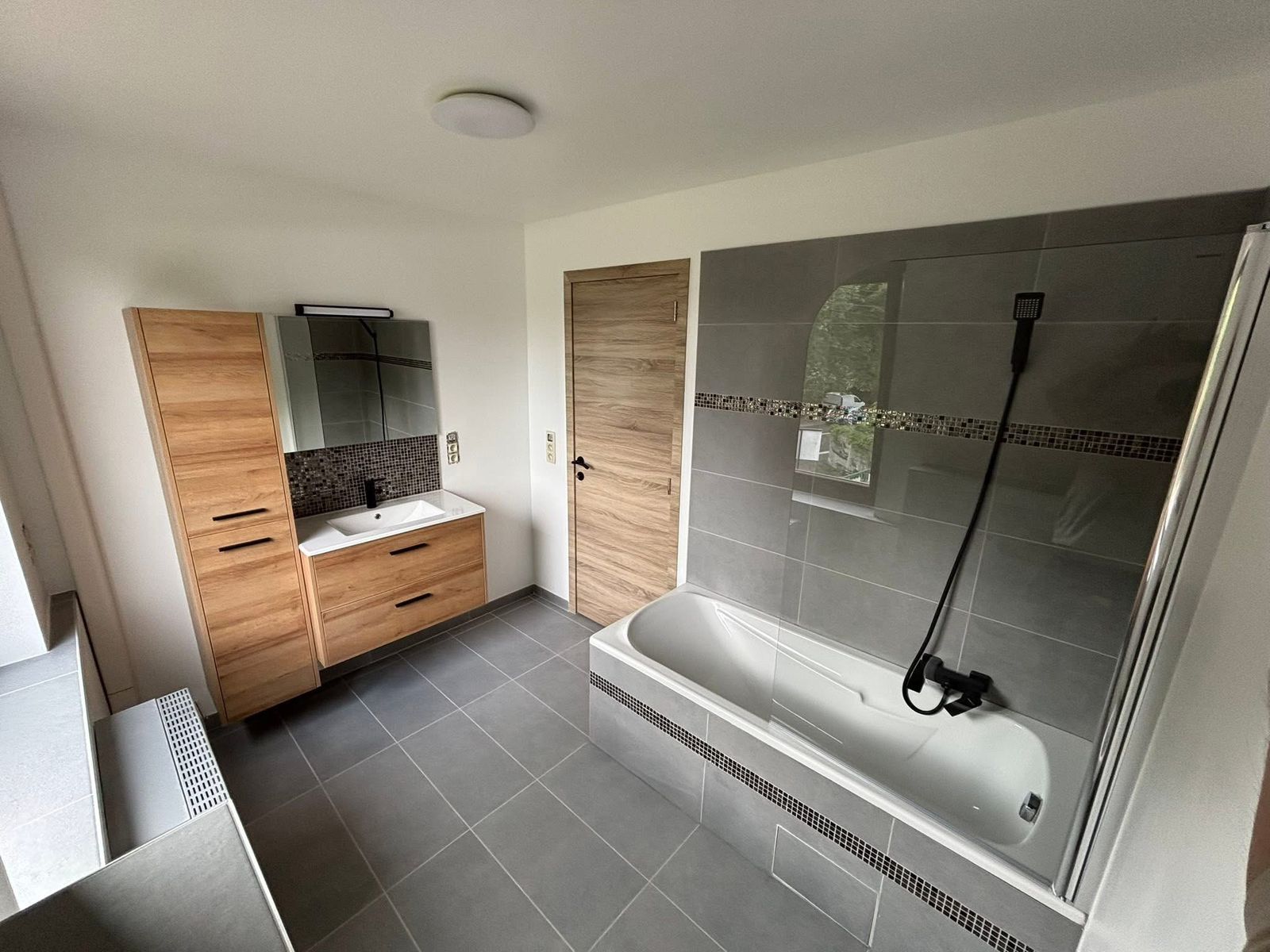 Salle de bain rénovée clé en main par EMG Rénovation — vasque suspendue en bois, baignoire et paroi de douche